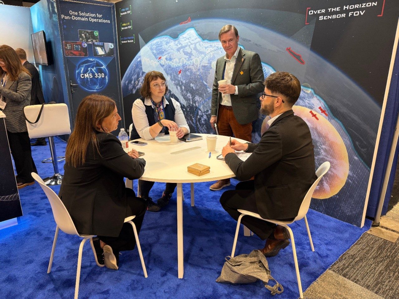 A group of individuals gathered at a table at the 2025 DEFSEC Lockheed Martin Canada booth